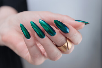 Woman's hand with long nails and green blue nail polish