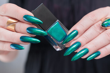 Woman's hand with long nails and green blue nail polish