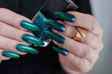 Woman's hand with long nails and green blue nail polish