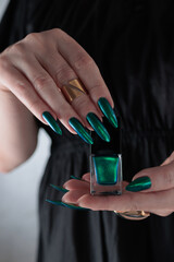 Woman's hand with long nails and green blue nail polish