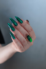 Woman's hand with long nails and green blue nail polish