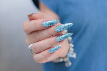 Female hand with long nails and bright light blue and silver manicure