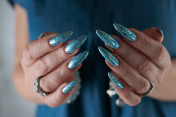 Female hand with long nails and bright light blue and silver manicure