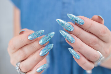 Female hand with long nails and bright light blue and silver manicure