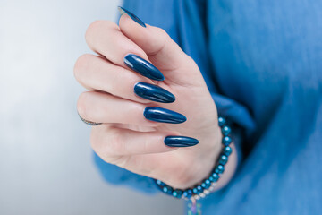 Woman's beautiful hand with long nails and dark blue manicure