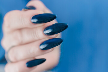 Woman's beautiful hand with long nails and dark blue manicure