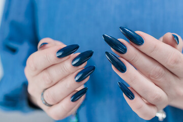 Woman's beautiful hand with long nails and dark blue manicure