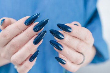Woman's beautiful hand with long nails and dark blue manicure