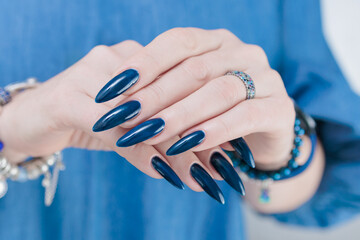 Woman's beautiful hand with long nails and dark blue manicure