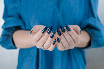 Woman's beautiful hand with long nails and dark blue manicure