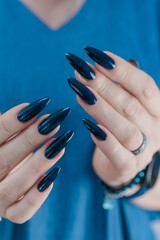 Woman's beautiful hand with long nails and dark blue manicure