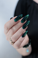 Woman's hand with long nails and black green nail polish