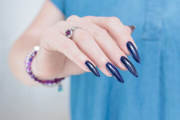 Woman's beautiful hand with long nails and dark blue manicure