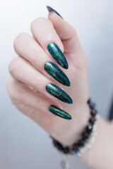 Woman's hand with long nails and green blue nail polish
