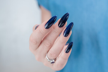 Woman's beautiful hand with long nails and dark blue manicure