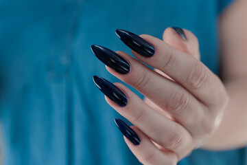 Woman's beautiful hand with long nails and dark blue manicure
