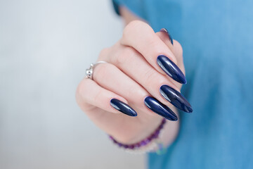 Woman's beautiful hand with long nails and dark blue manicure
