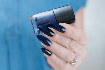 Woman's beautiful hand with long nails and dark blue manicure