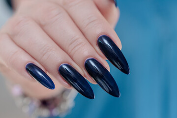 Woman's beautiful hand with long nails and dark blue manicure