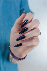 Woman's beautiful hand with long nails and dark blue manicure