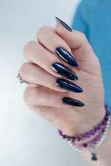 Woman's beautiful hand with long nails and dark blue manicure
