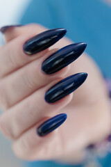 Woman's beautiful hand with long nails and dark blue manicure