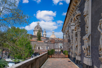 CATANIA, ITALY. Ornate baroque courtyard and stone staircase of the historic Palazzo Biscari, featuring classical sculptures and architectural details under a blue sky in Sicily.