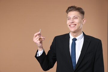 Real estate agent holding key with house shaped keychain on beige background
