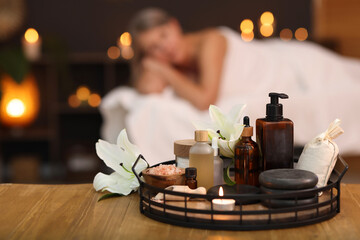 Senior woman relaxing on massage couch indoors, focus on different spa products and lily flowers