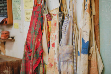 Colourful aprons in a workshop, showcasing an artist's creative and messy studio