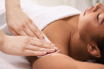 Woman undergoing wax epilation procedure indoors, closeup