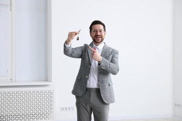 Real estate agent holding key with house shaped keychain indoors