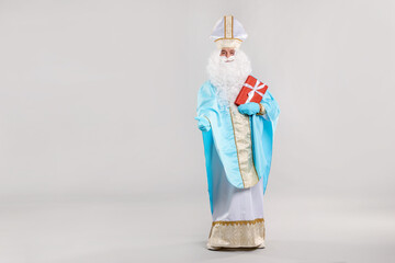 Saint Nicholas with Christmas gift on gray background