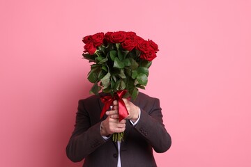 Senior man with bouquet of red roses on pink background