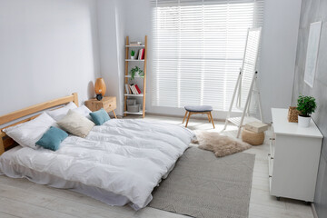 Comfortable bed, dresser and mirror in bedroom