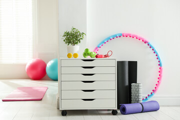 Different fitness equipment and chest of drawers indoors