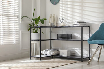 Console table with different decor and chair near white wall indoors. Interior design