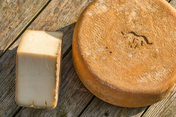 Traditional Ossau-Iraty cheese on a wooden table in the rural setting in France.