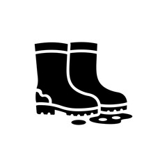 Farm Boots Next to Puddle with Muddy Soles