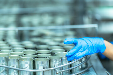 Workers wearing protective clothing and masks work in a food processing plant. Hygiene, quality control, manufacturing, and industrial production concept.