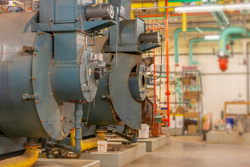 Old boilers in mechanical room in basement of building.