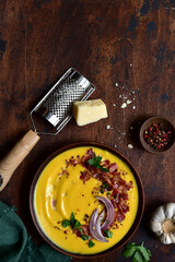 Autumn pumpkin soup with smoked bacon in a clay bowl . Top view with copy space.