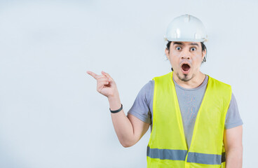 Surprised engineer constructor pointing side advertising space isolated. Amazed engineer pointing...