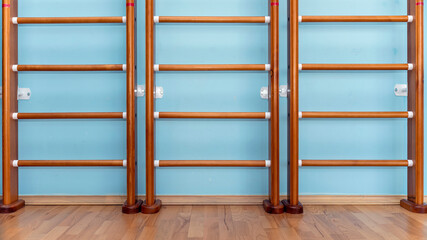 Wooden wall bars positioned against a blue wall in a gym, encouraging physical activity and promoting a healthy lifestyle through exercise