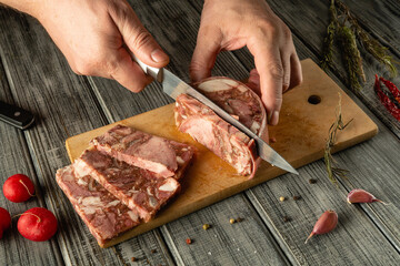 Hands skillfully slice meat on a wooden cutting board, surrounded by fresh shallots, radishes, and herbs in a cozy kitchen environment