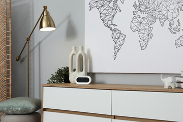 Dresser with different decor, lamp and pouf near grey wall indoors. Interior design