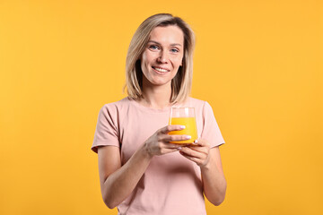 Woman with glass of juice on orange background. Refreshing drink