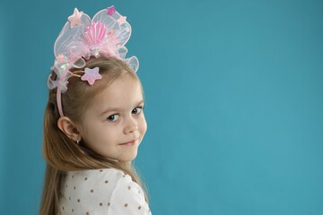 Fototapeta premium Cute little girl with beautiful headband on blue background. Space for text