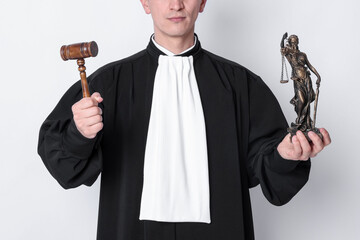 Judge with mallet and statue of Lady Justice on light background, closeup