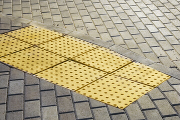 Path for the blind. Braille blocks, yellow blocks of tactile paving for blind people. White cane...